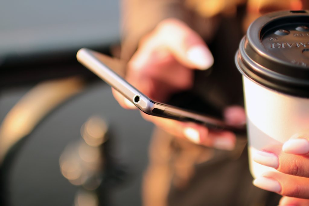 lady holding a mobile phone and a cup of coffee