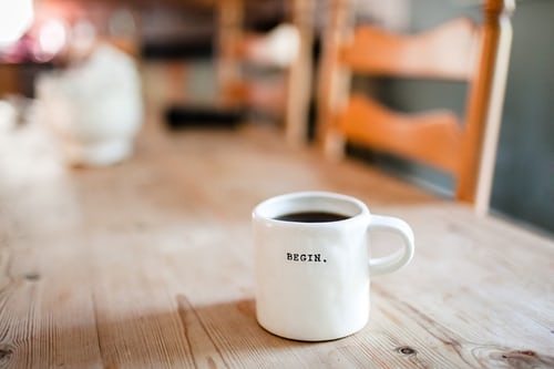 a white coffee mug with a text begin on a table